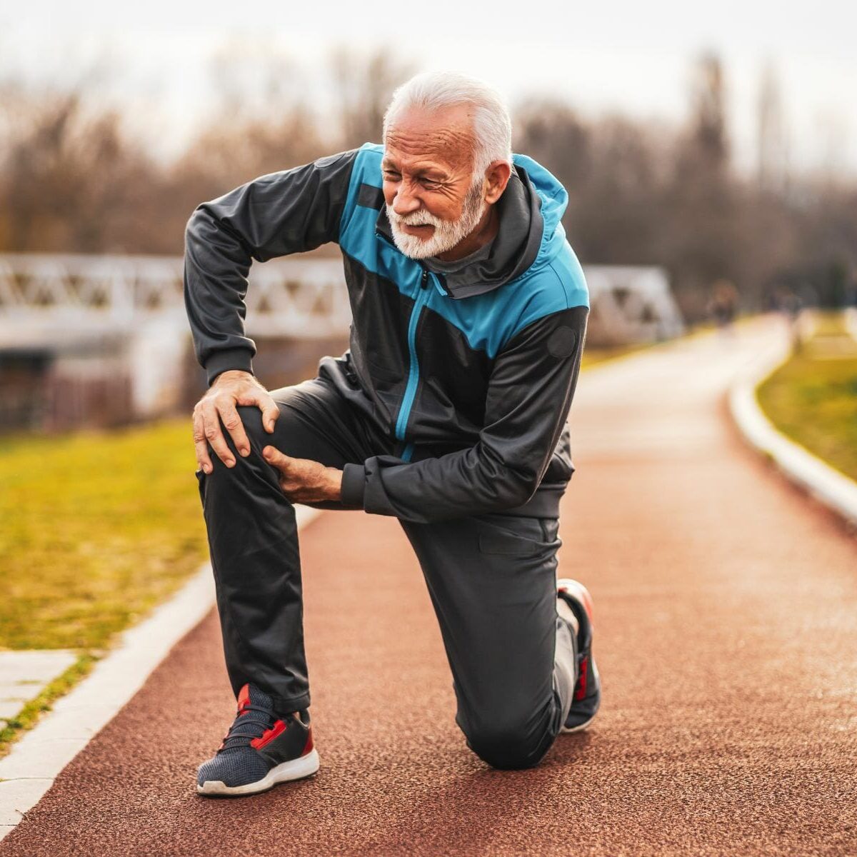 Active senior man is having pain in knee while jogging.